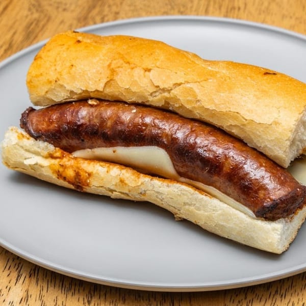 A grilled sausage sub sandwich with melted cheese on a light gray plate from Lee's Deli.