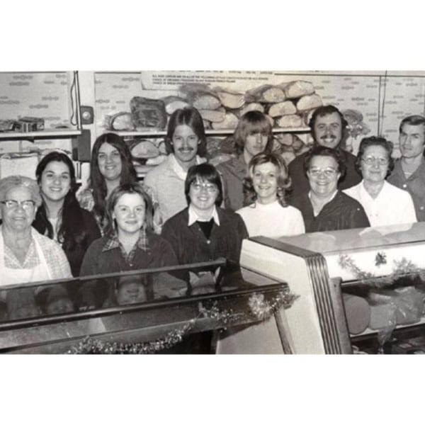 Black and white photo of a large group of Lee's Deli employees smiling behind a counter.