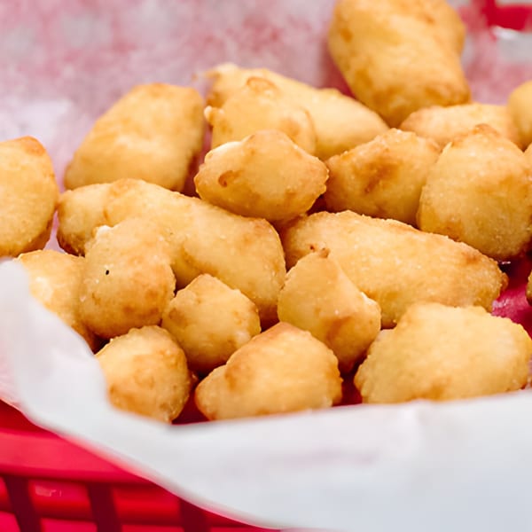 Golden-brown fried cheese curds in a red basket lined with white paper at Lee's Deli.